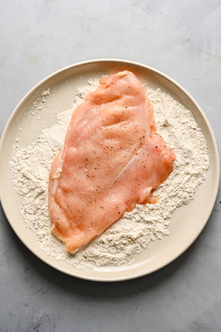 Overhead view of chicken getting coated in flour.