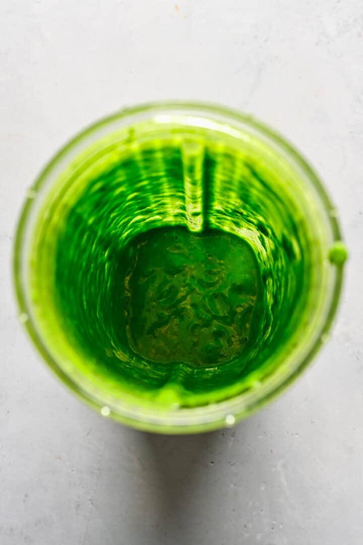 Overhead view of pesto vinaigrette in a blender bottle.