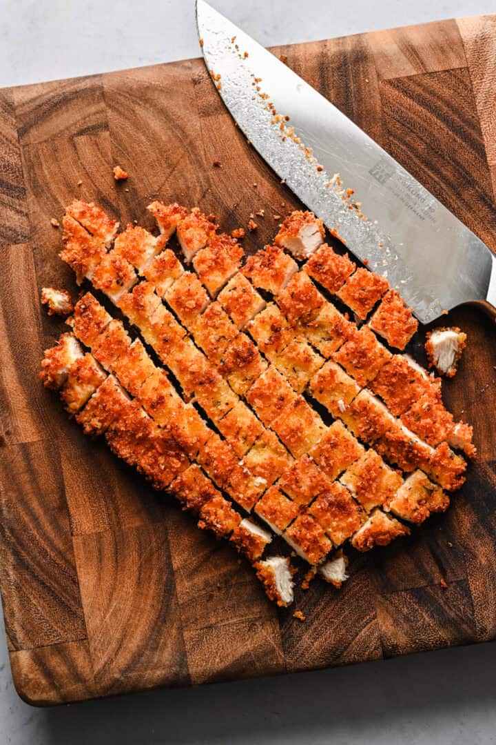 Overhead view of chicken cutlet cut into pieces.