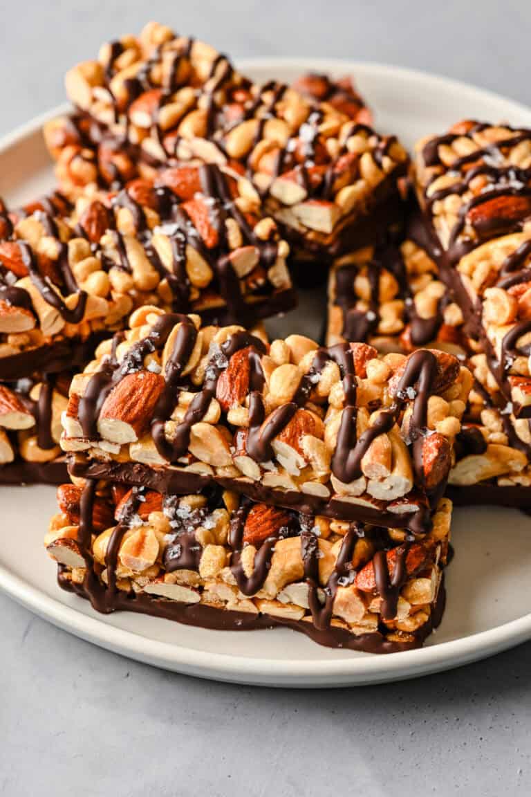 Walnut and almond granola bars drizzled with chocolate on a white plate.
