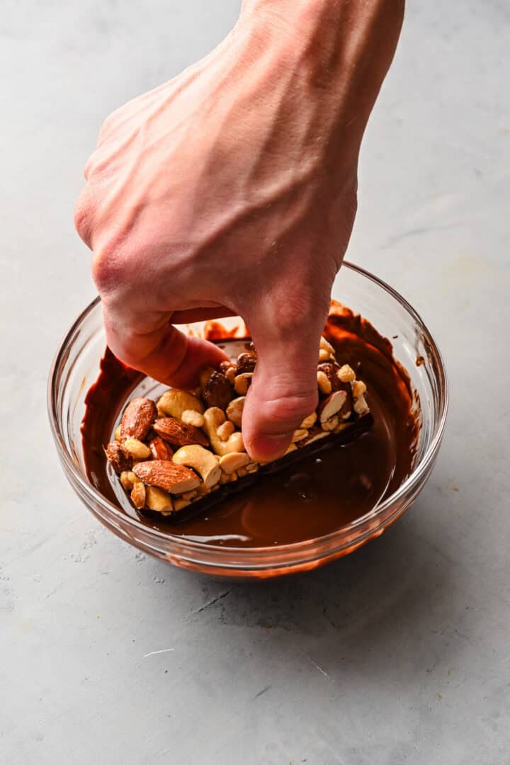 Dipping nut bar in chocolate.