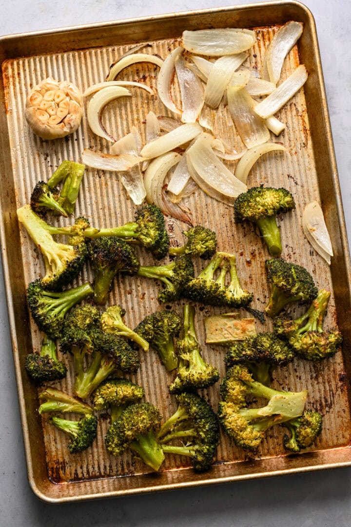 Overhead view of roasted broccoli and onions on a sheet pan.