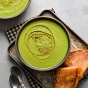Overhead view of broccoli soup in a bowl alongside grilled cheese.