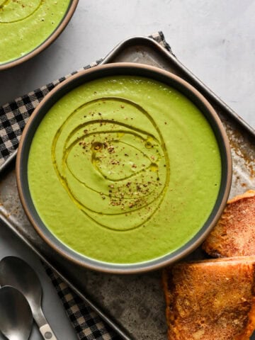 Overhead view of broccoli soup in a bowl alongside grilled cheese.
