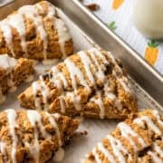 Close up side view of carrot cake scone with cream cheese glaze on a sheet pan.