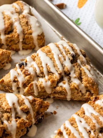 Close up side view of carrot cake scone with cream cheese glaze on a sheet pan.