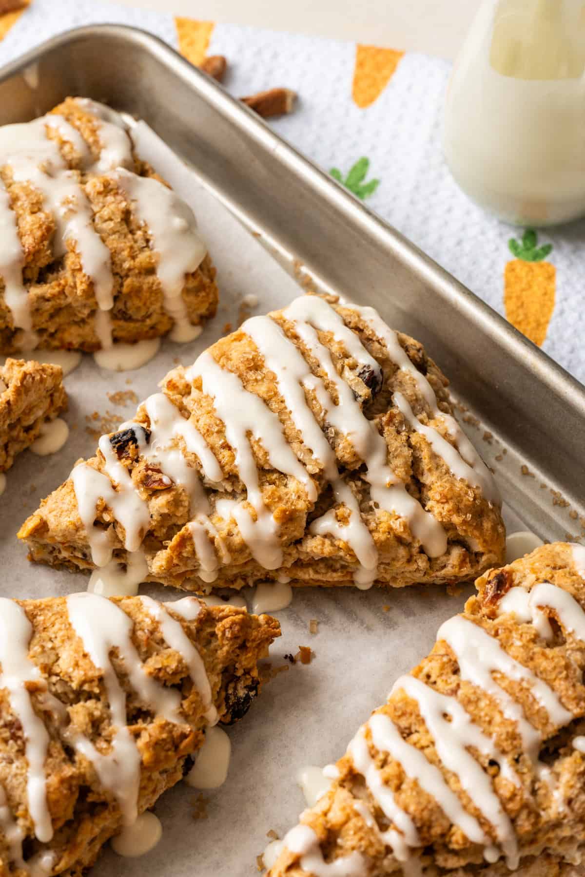 Close up side view of carrot cake scone with cream cheese glaze on a sheet pan.