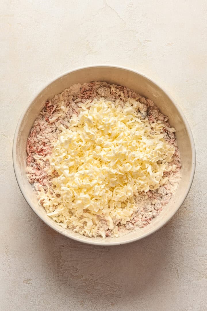 Grated butter on top of dry ingredients for carrot cake scones.