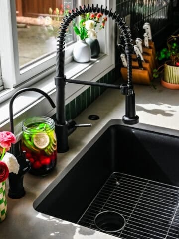 Reverse osmosis tap installed into countertop next to a vase of flowers and jar of infused water.