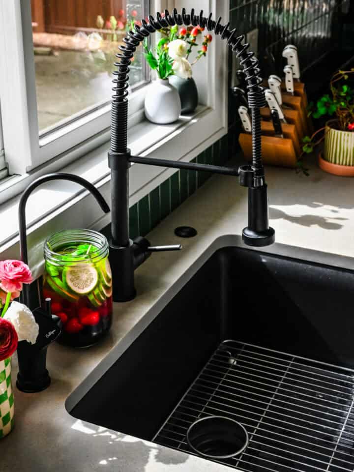 Reverse osmosis tap installed into countertop next to a vase of flowers and jar of infused water.