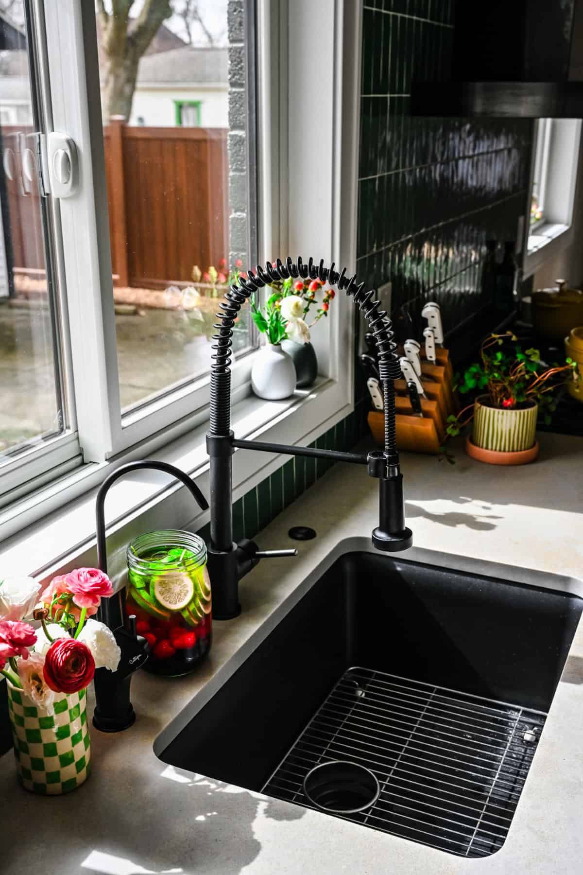 Reverse osmosis tap installed into countertop next to a vase of flowers and jar of infused water. 