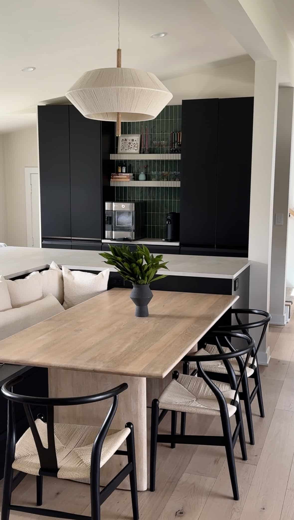 View of kitchen table and black cabinets with green tile. 