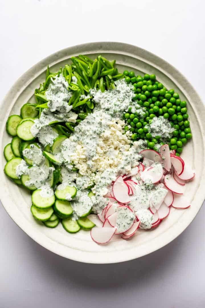 Overhead view of cucumber pea salad with dressing poured over the top.