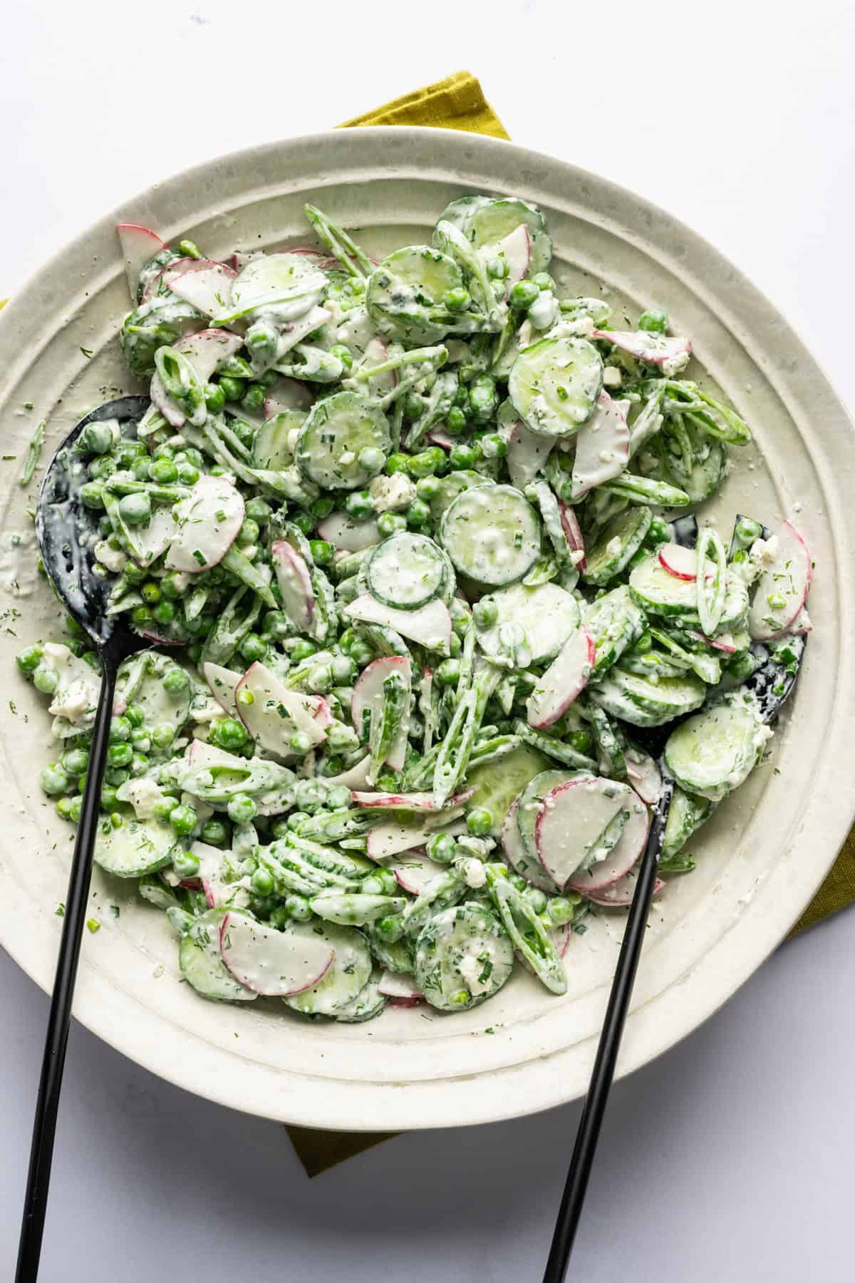 Overhead view of creamy cucumber pea salad in a bowl.