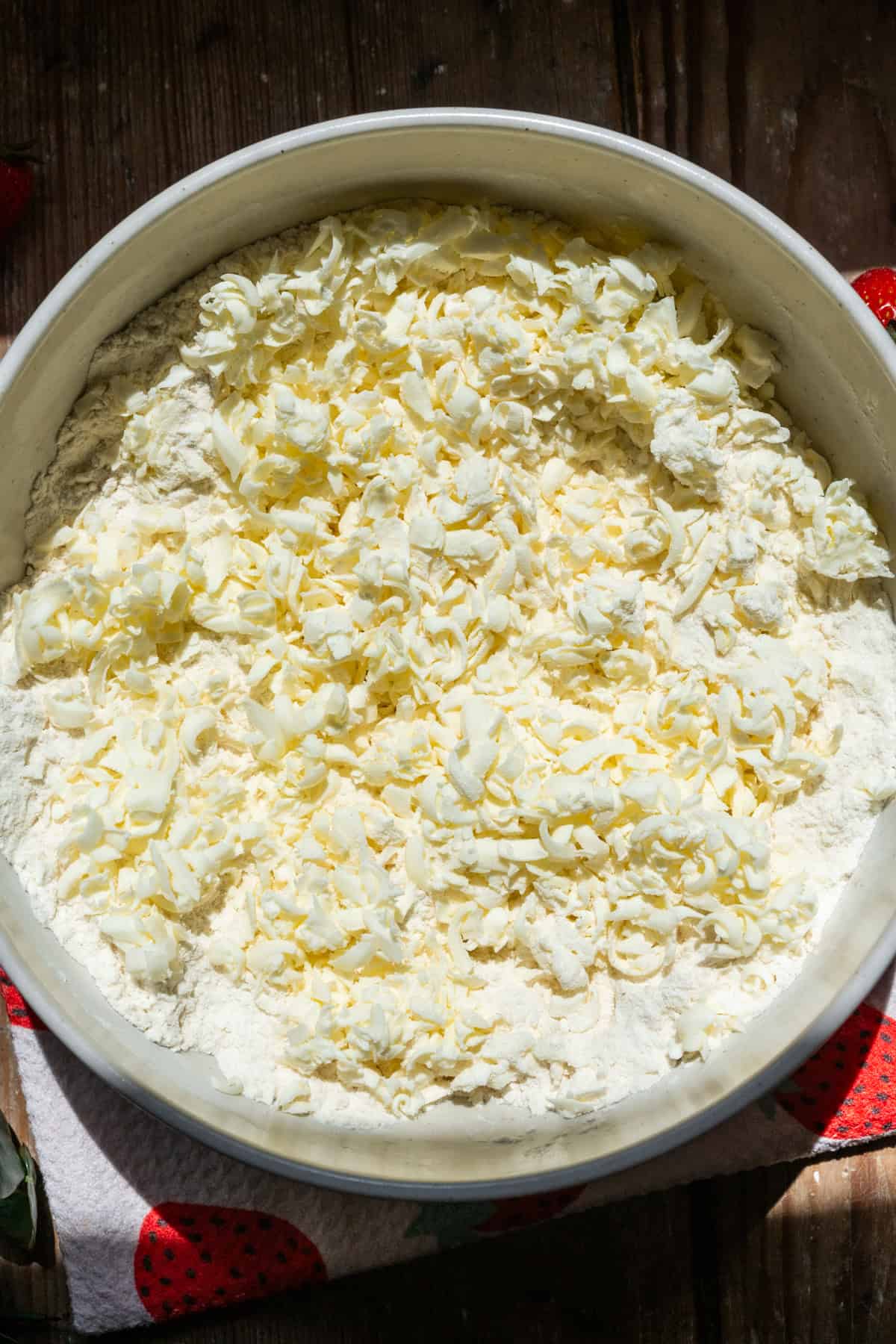 Cold grated butter in a bowl with dry ingredients. 
