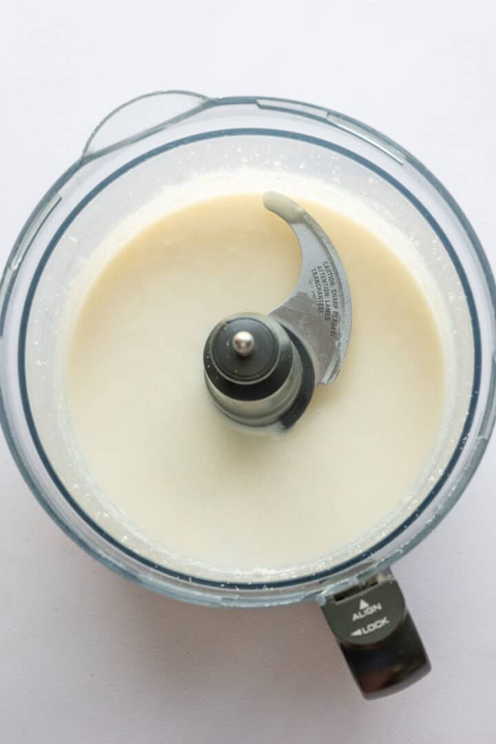 Shredded coconut in food processor after blending to make homemade coconut butter. 
