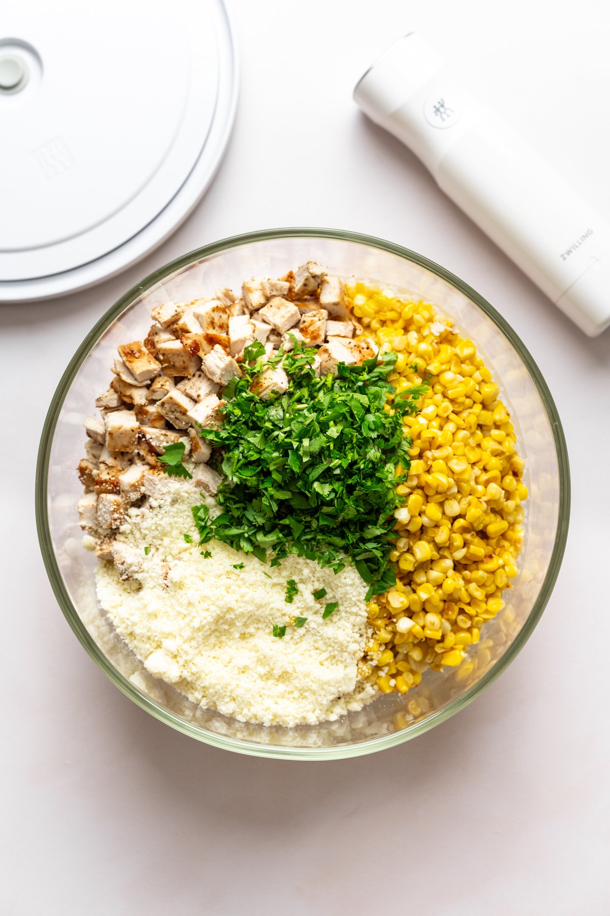 Elote pasta salad ingredients in large glass bowl before mixing together.