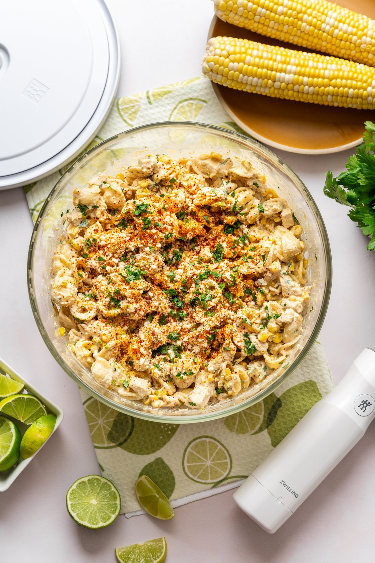 Overhead view of elote pasta salad with grilled chicken in large glass bowl. 
