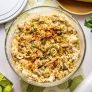 Overhead view of elote pasta salad with grilled chicken in large glass bowl.