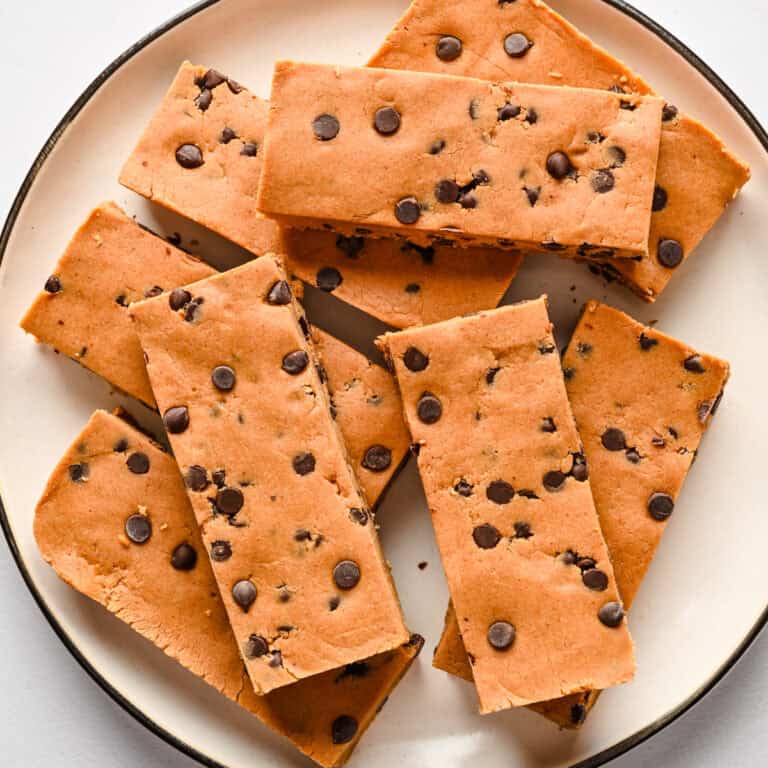 Chewy chocolate chip cookie bars on a white plate with a black rim.