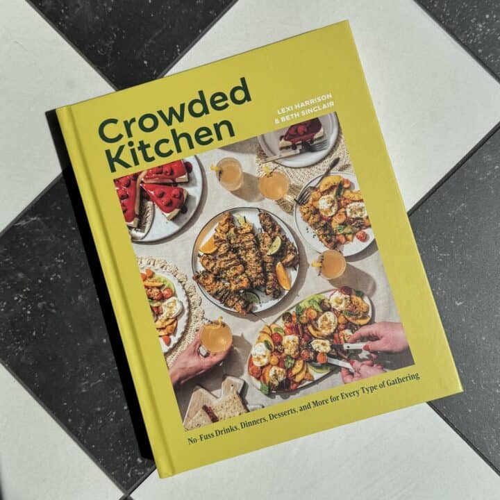 Crowded Kitchen cookbook cover with colorful food and drinks on a table, featuring crowd-pleasing recipes.