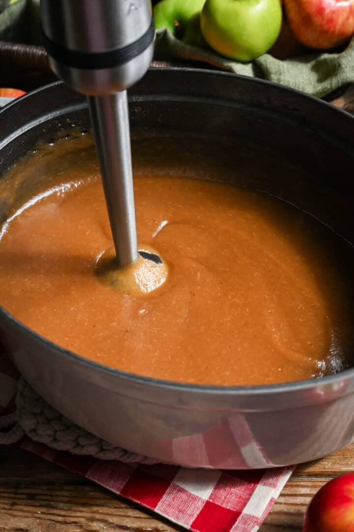 Blending apple butter in a large pot with an immersion blender. 