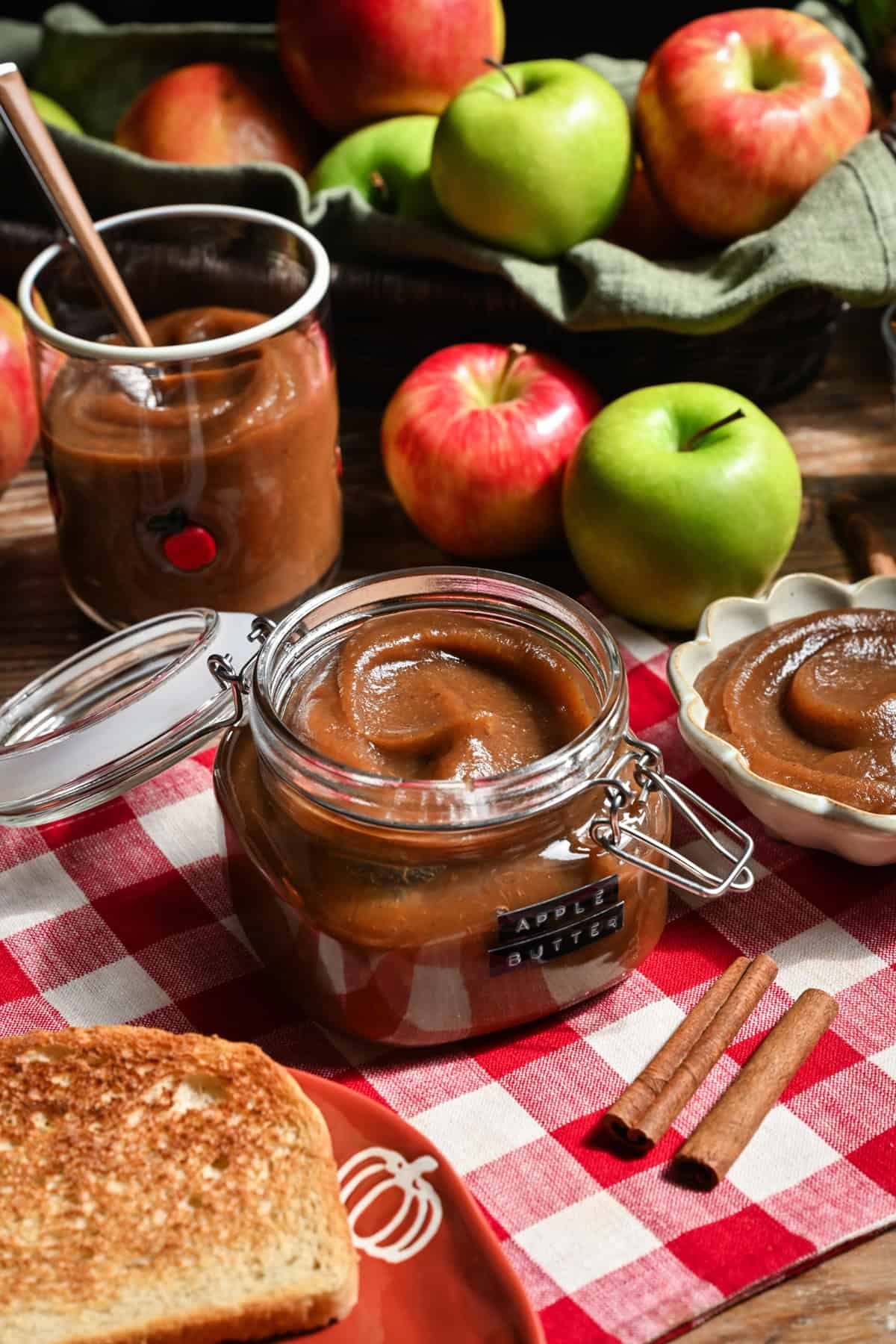 Apple butter in a jar with apples in the background.