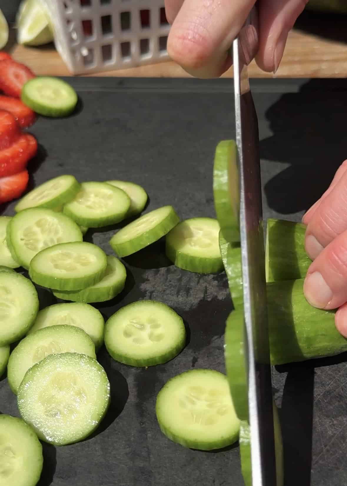 Slicing cucumbers on cutting board. 