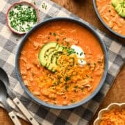 Overhead view of creamy buffalo chicken chili topped with shredded cheese and avocado.