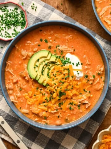Overhead view of creamy buffalo chicken chili topped with shredded cheese and avocado.