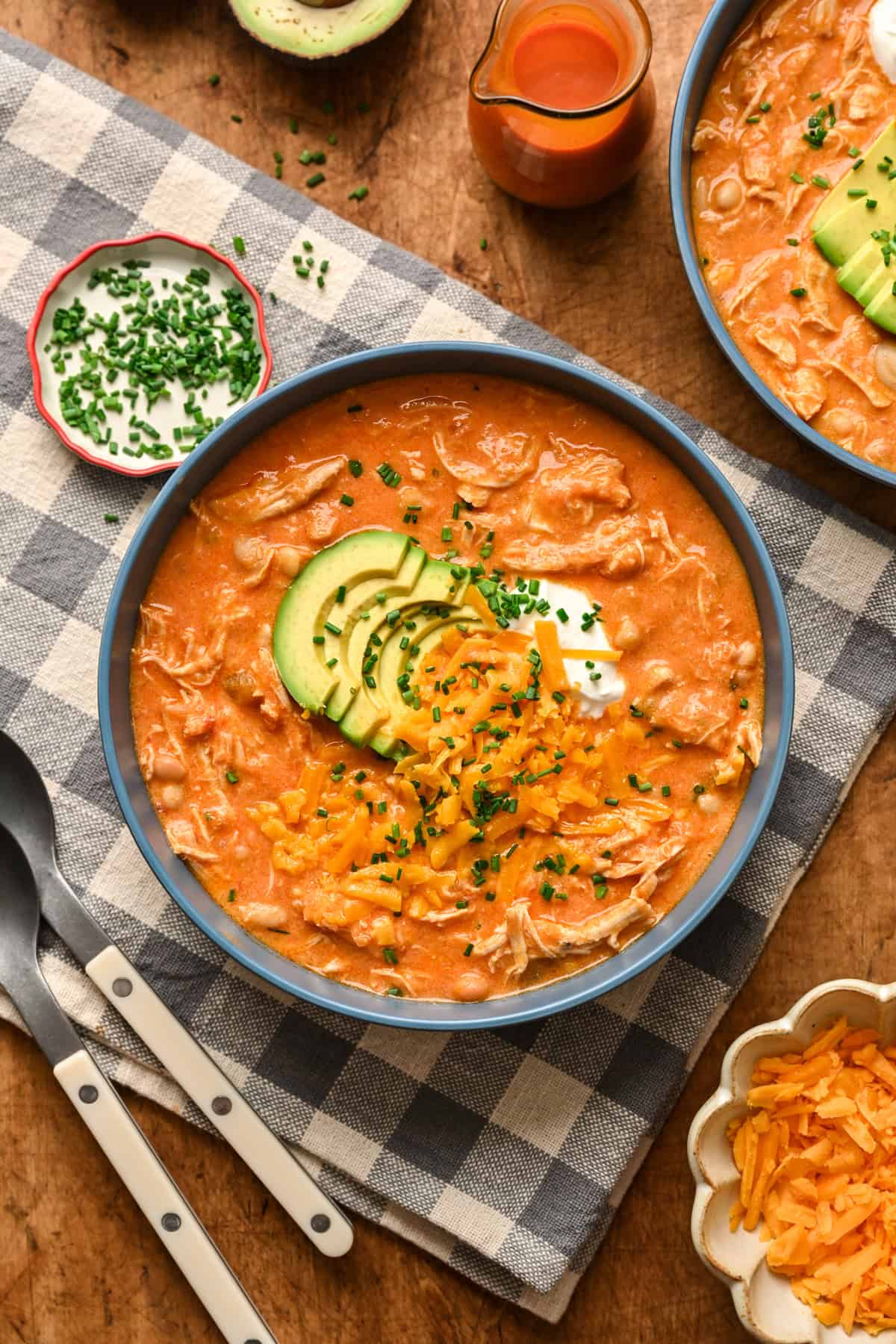Overhead view of creamy buffalo chicken chili topped with shredded cheese and avocado.