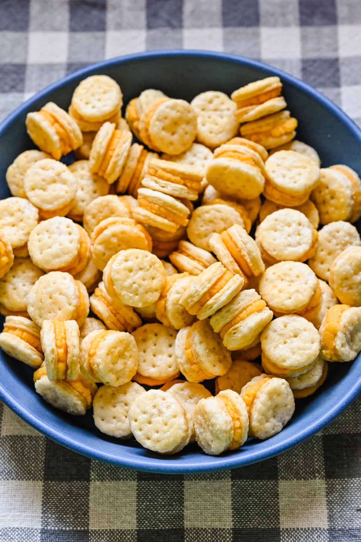 Overhead view of homemade ritz cheese cracker sandwiches in a blue bowl.