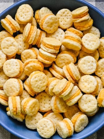 Overhead view of homemade ritz cheese cracker sandwiches in a blue bowl.