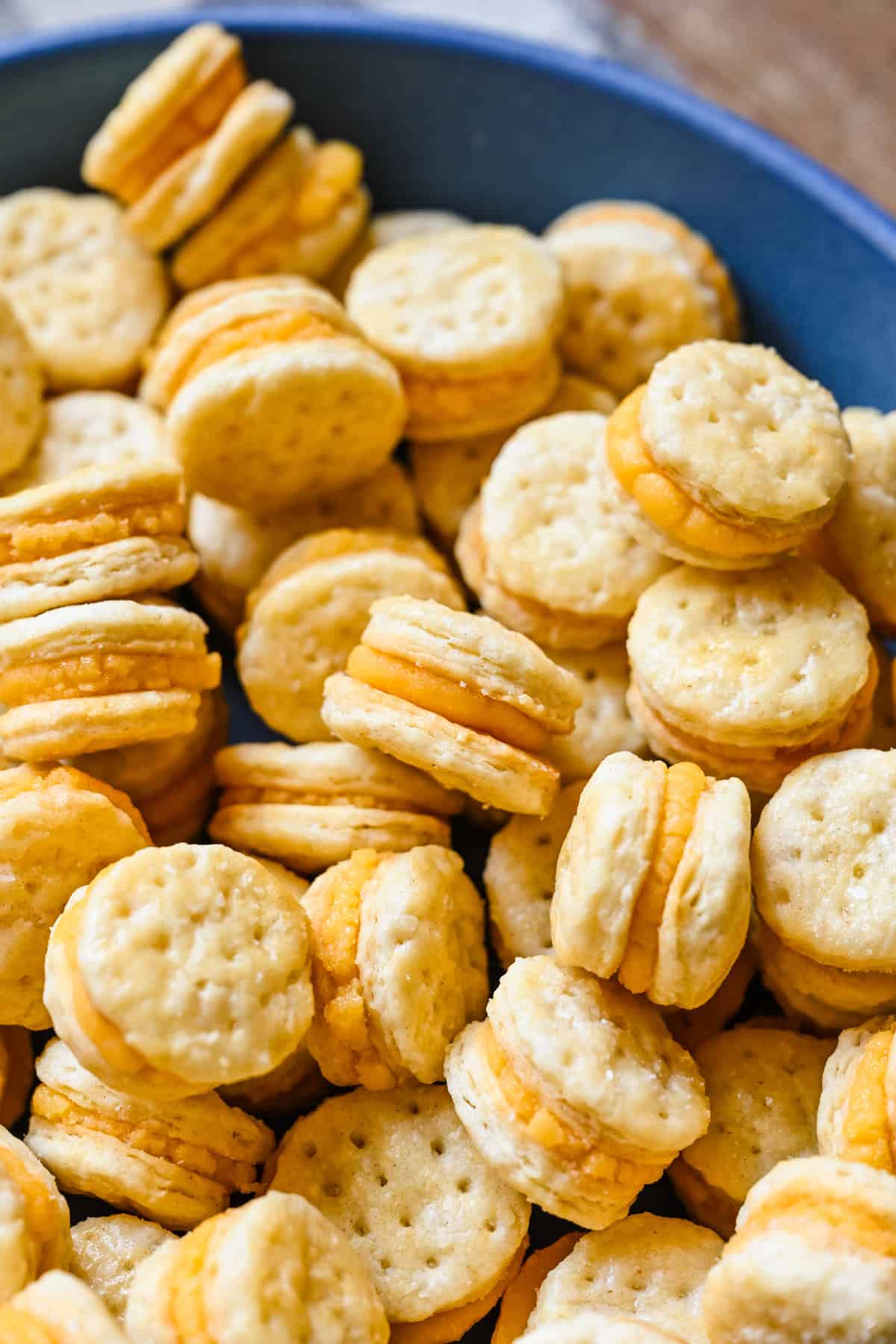 Close up view of homemade ritz cheese cracker sandwiches in a blue bowl.