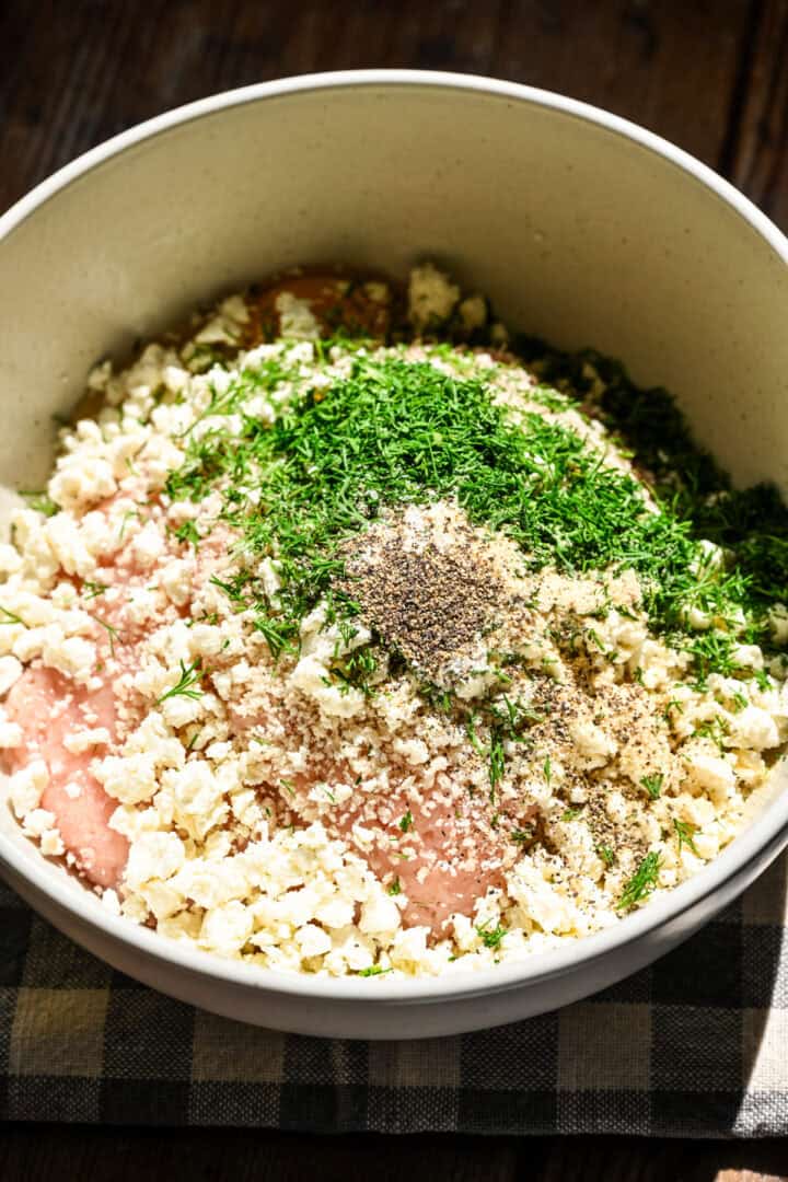 Dill and feta chicken meatball mixture in a bowl before mixing together.