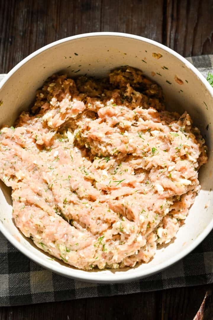 Dill and feta chicken meatball mixture in a bowl after mixing together.