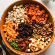 Overhead view of bacon apple cheddar arugula salad before tossing all of the ingredients together in a wood salad bowl.