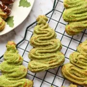 Close up overhead view of christmas tree shaped churros coated in matcha sugar on a christmas tree cooling rack.