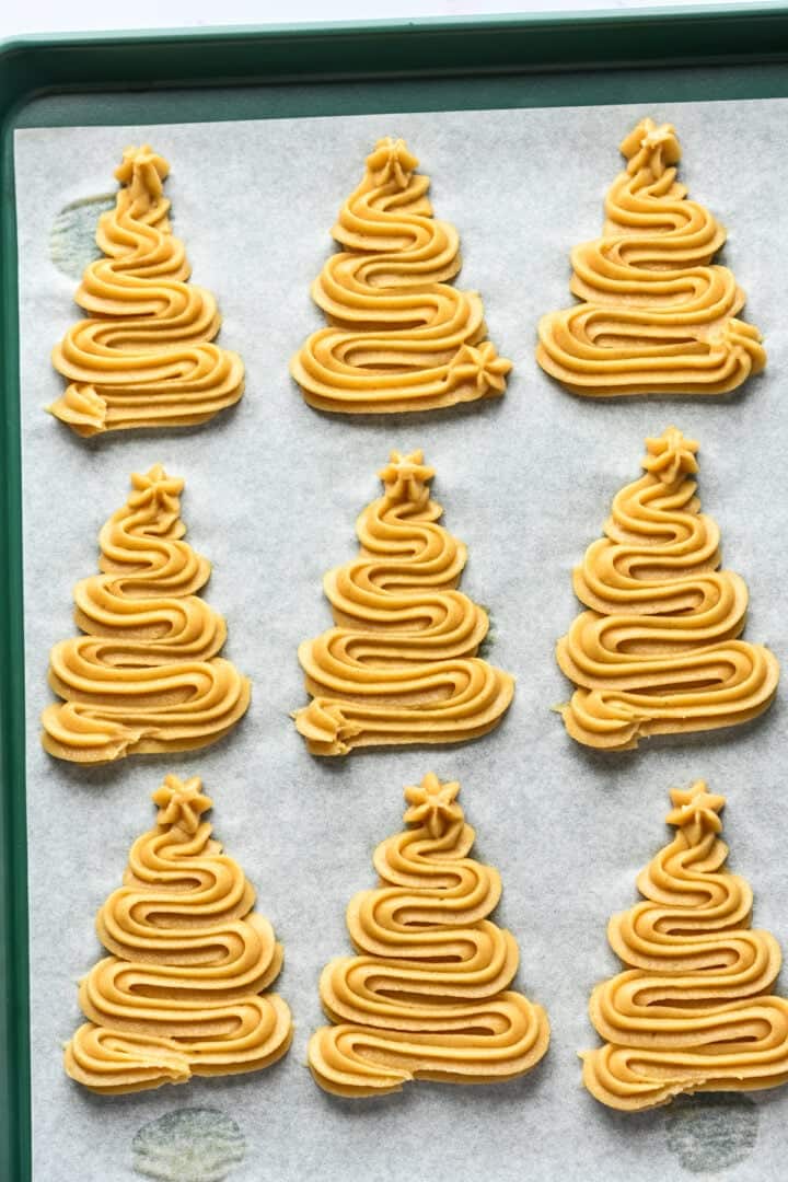 Christmas tree shaped churros piped onto a baking sheet before frying.
