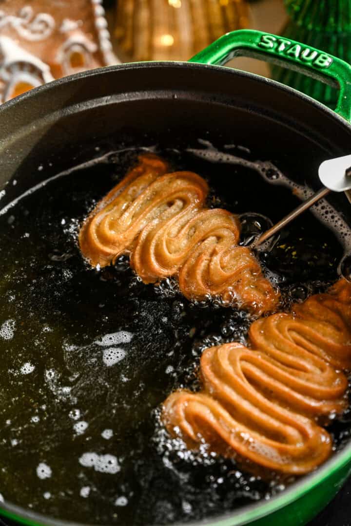 Christmas tree churros frying in a large pot.