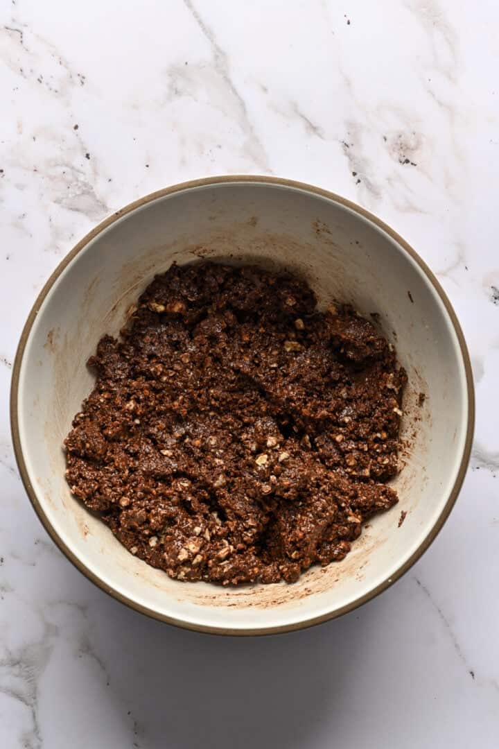 Overhead view of nutella, chopped wafer cookies and chopped hazelnuts in a bowl before mixing.