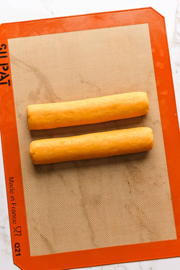 Dough rolled into two orange logs.