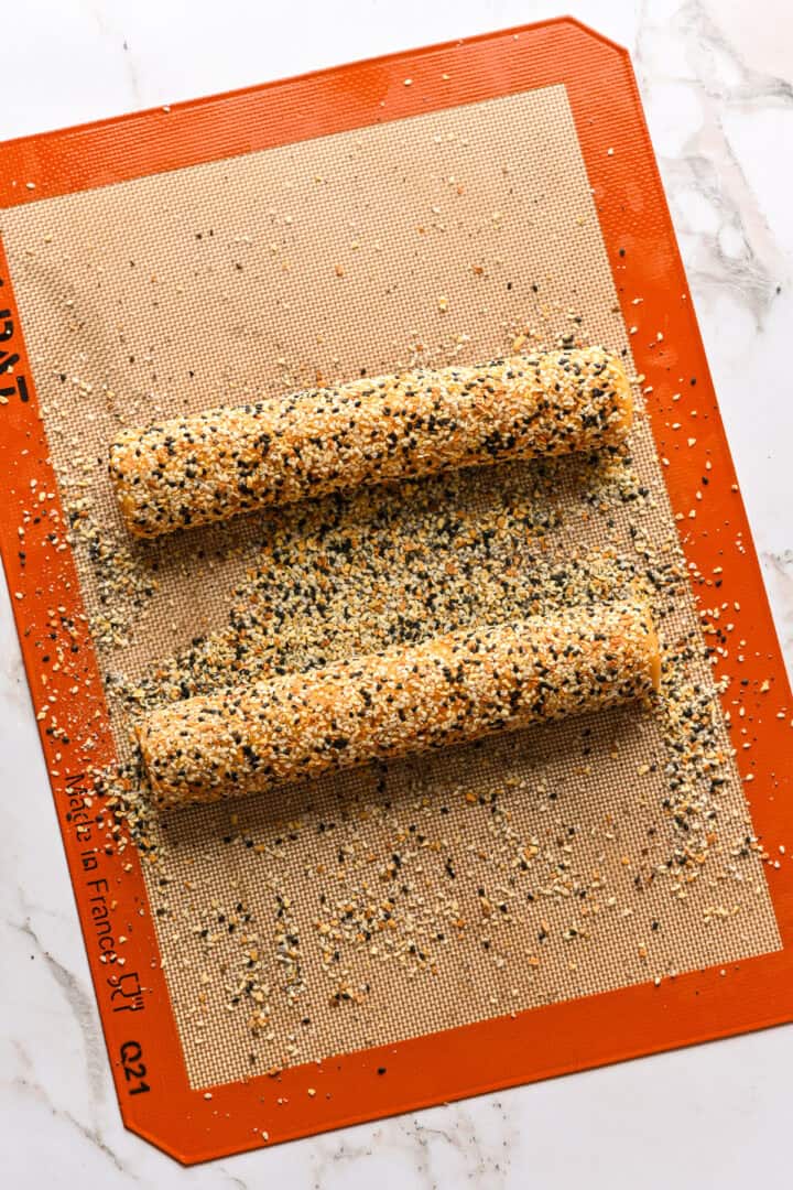 Dough logs after crusting in everything bagel seasoning.