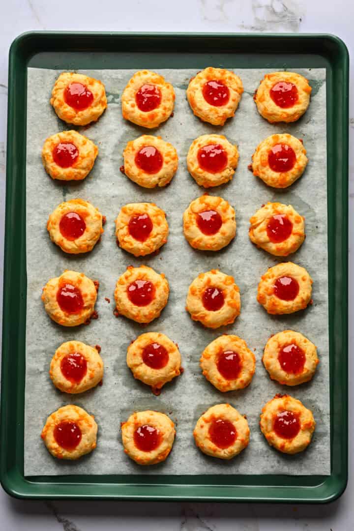 Overhead view of cheesy thumbprints on a sheet pan.