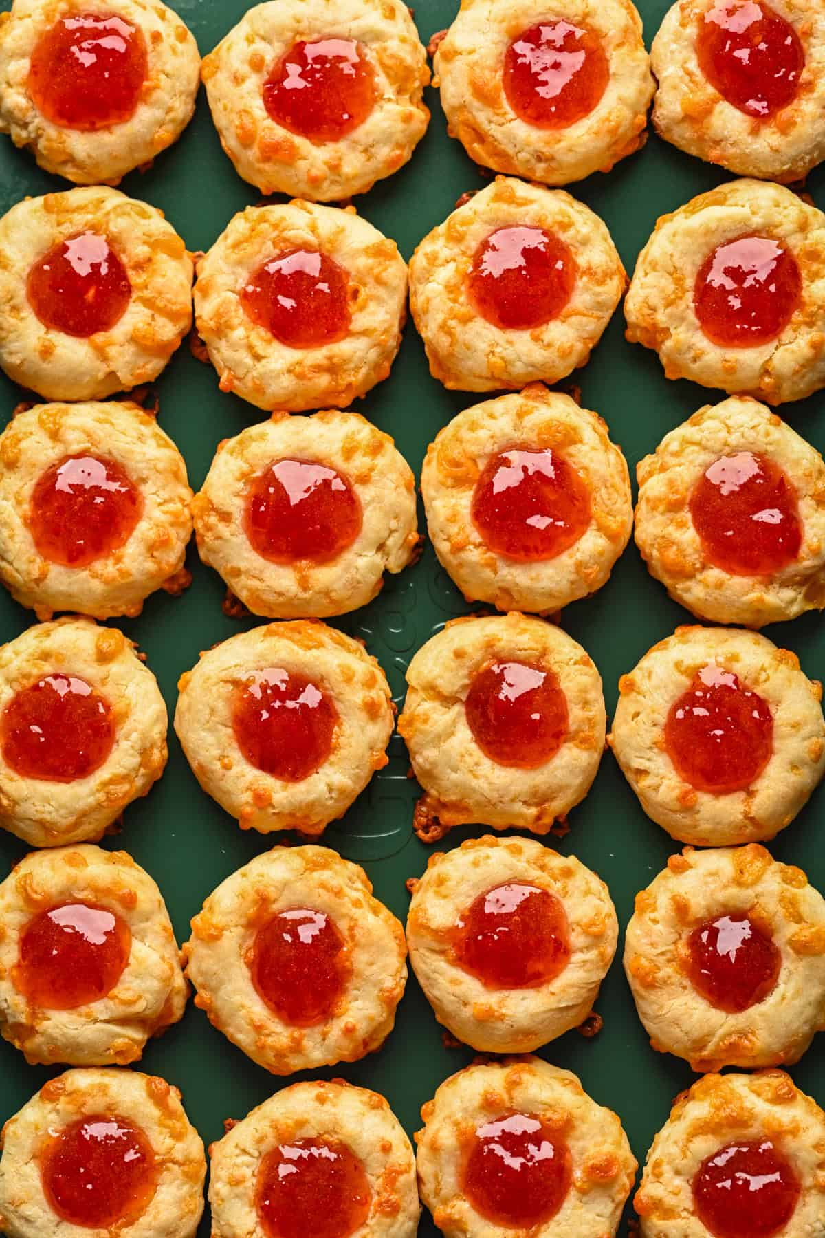 Overhead view of cheesy thumbprints on a sheet pan.
