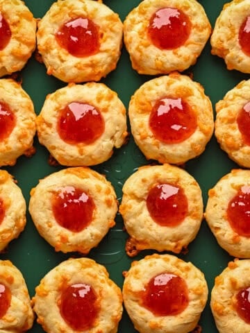 Overhead view of cheesy thumbprints on a sheet pan.