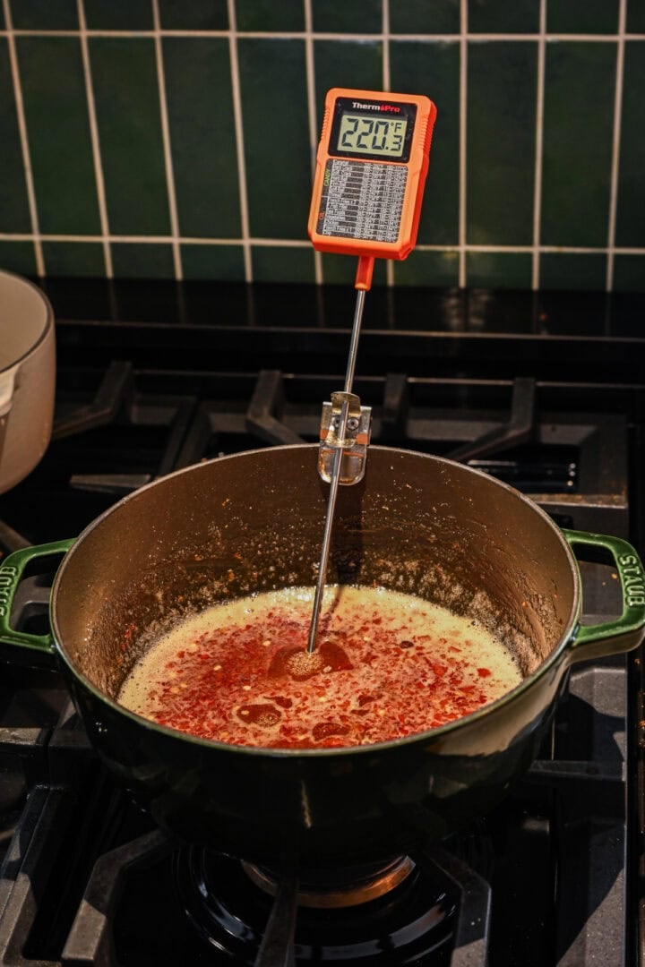 Front view of pepper jelly with thermometer in pot.