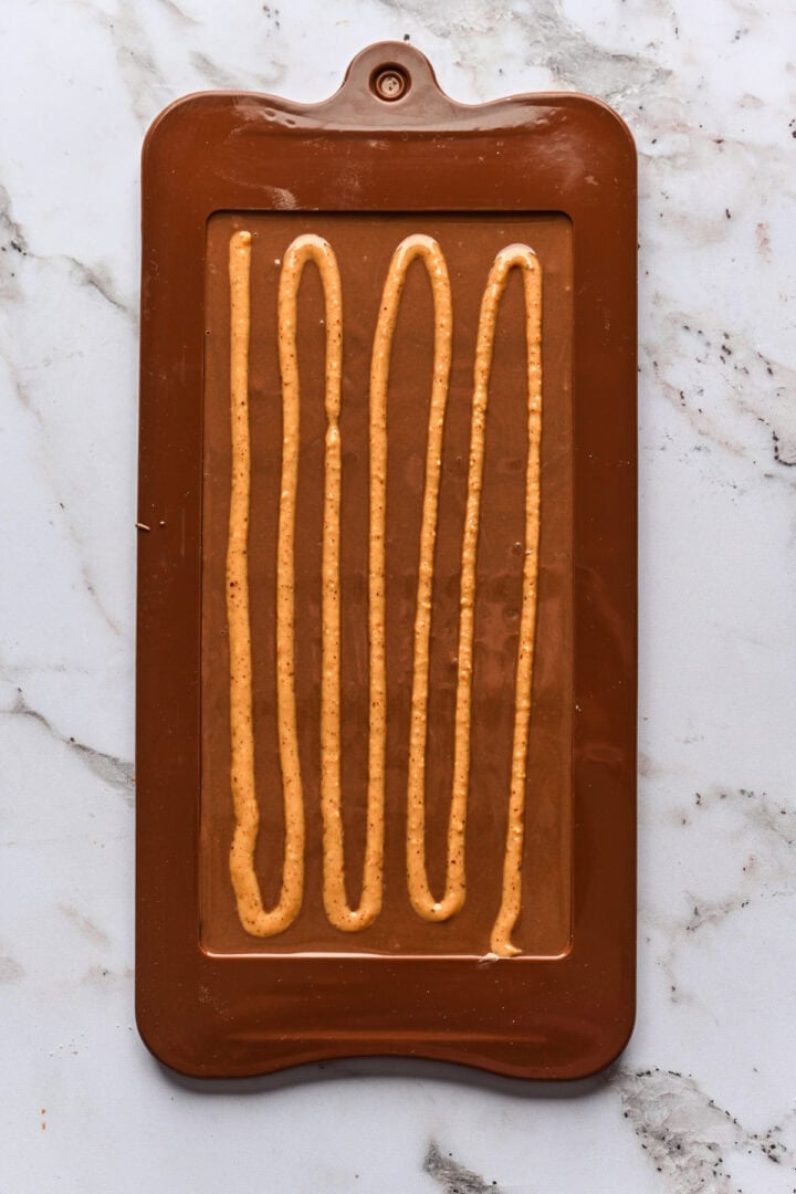 Overhead view of peanut butter squiggles on chocolate bar.