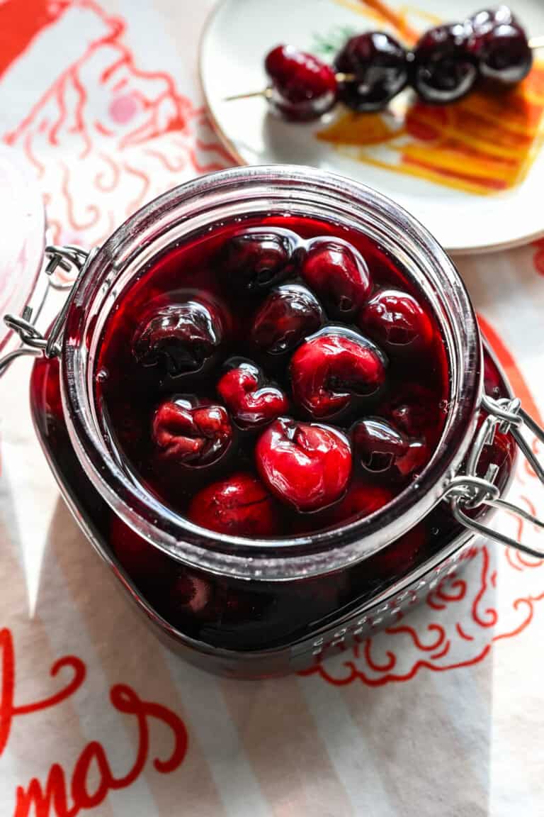 Close up view of cocktail cherries in a glass jar.