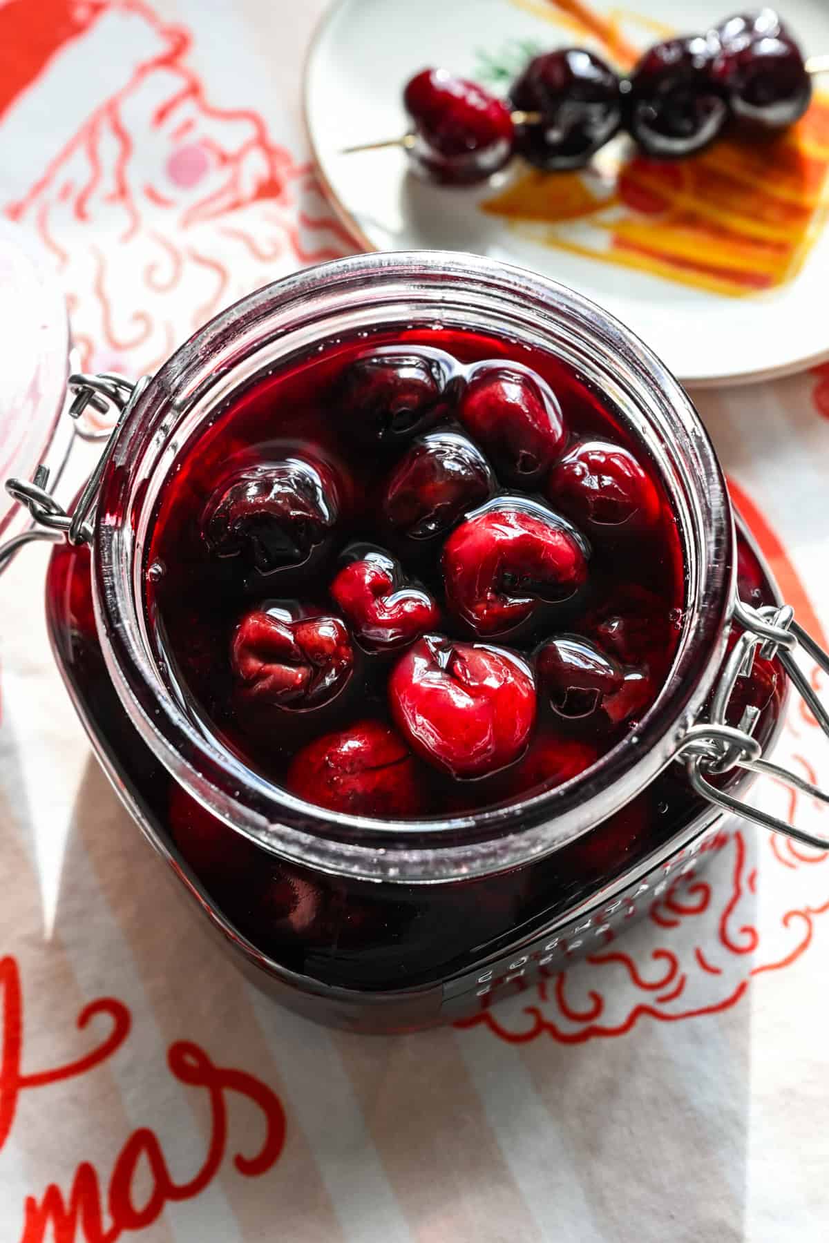 Close up view of cocktail cherries in a glass jar.
